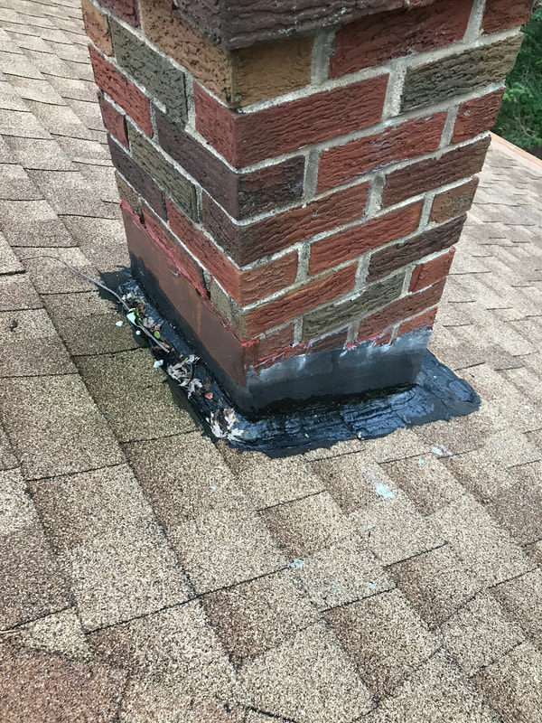 Chimney flashing with roofing sealant covering the flashing done improperly and observed during a home inspection by Dairyland Home Inspection.
